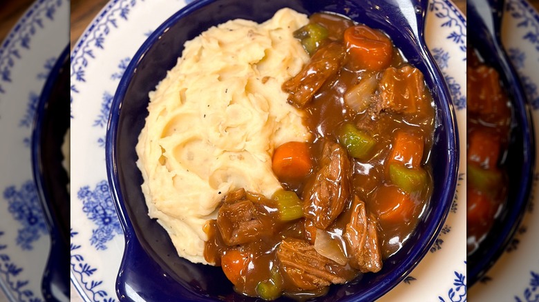 A blue dish with pot roast and mashed potatoes