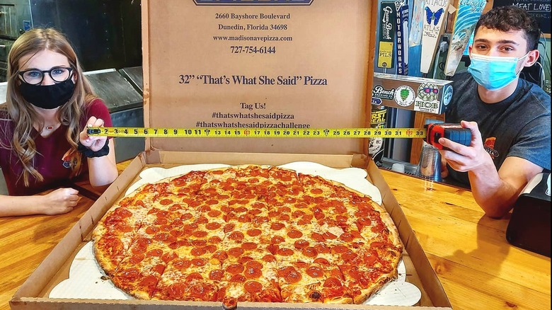 Employees measuring giant pizza