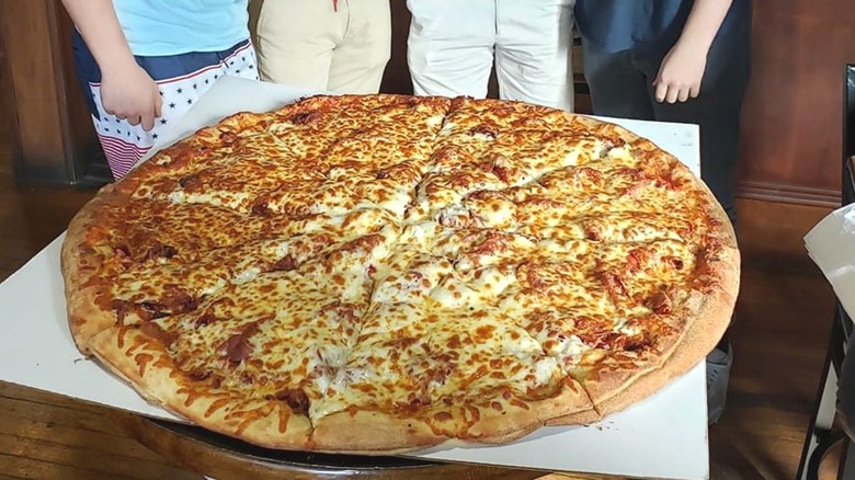 Group with giant pizza on table