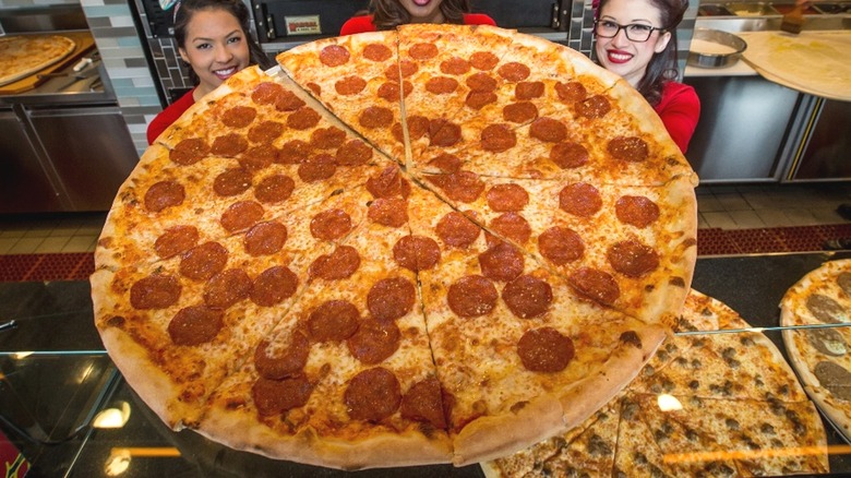 Employees holding giant pepperoni pizza