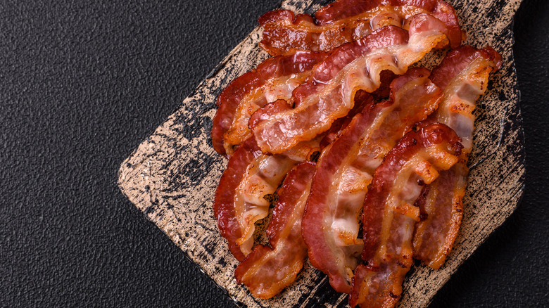 Cutting board with cooked bacon sitting on top