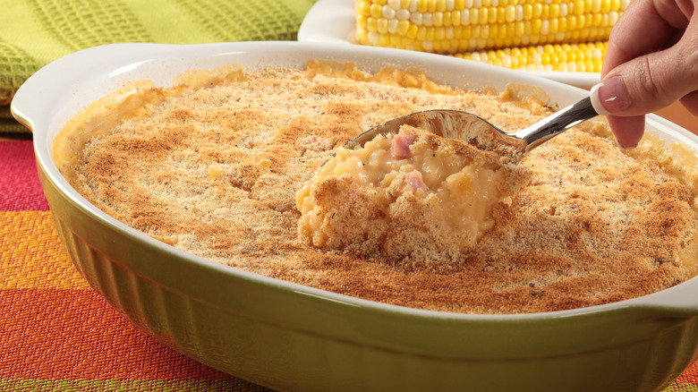 A person scooping a spoonful of scalloped corn