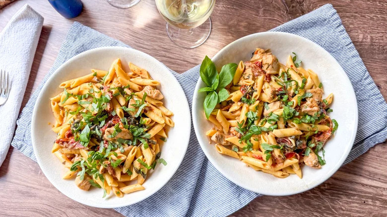 Two bowls of High Protein Marry Me Chicken Pasta with fresh basil on top