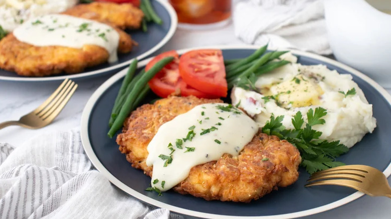 Chicken-fried chicken and country gravy served with tomatoes and green beans