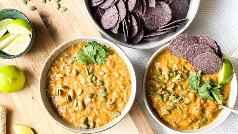 Hearty white chicken and navy bean chili garnished with pumpkin seeds, parsley, and lime