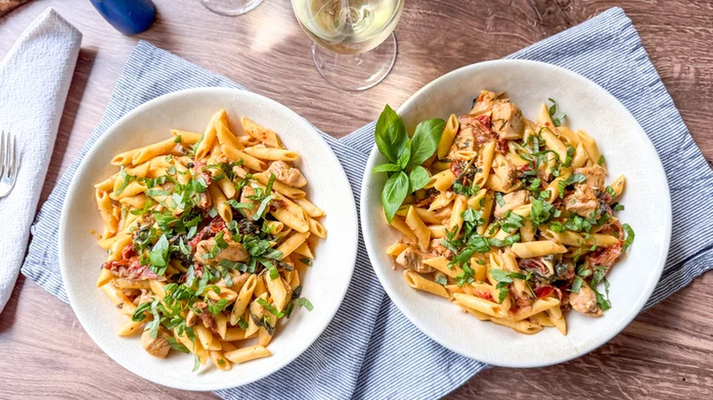 High protein marry me chicken pasta served in two white bowls