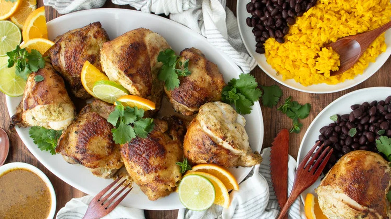 Pan-Seared Cuban mojo chicken served with rice and beans on various serving platters.
