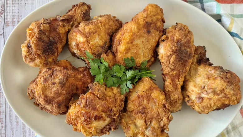 Simple classic fried chicken served on a white plate with a herb garnish