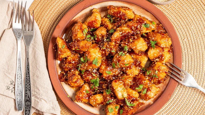 Sweet And spicy sesame chicken topped with cilantro leaves