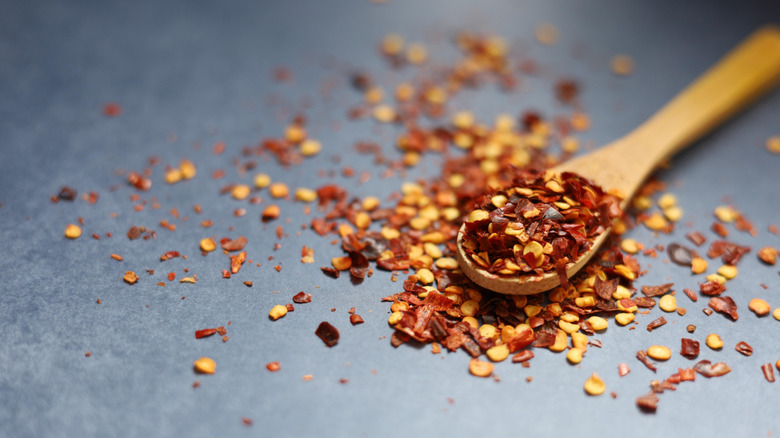 A wooden spoon full of crushed red pepper.