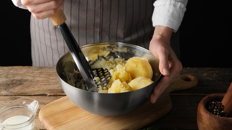 Person mashing potatoes with masher