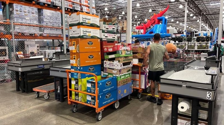 Person buying carts of bulk goods at checkout counter in Costco
