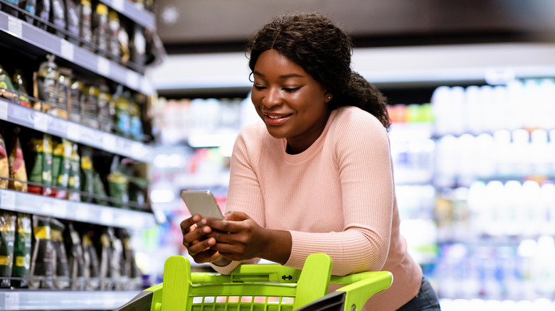Woman looking at her phone in grocery store