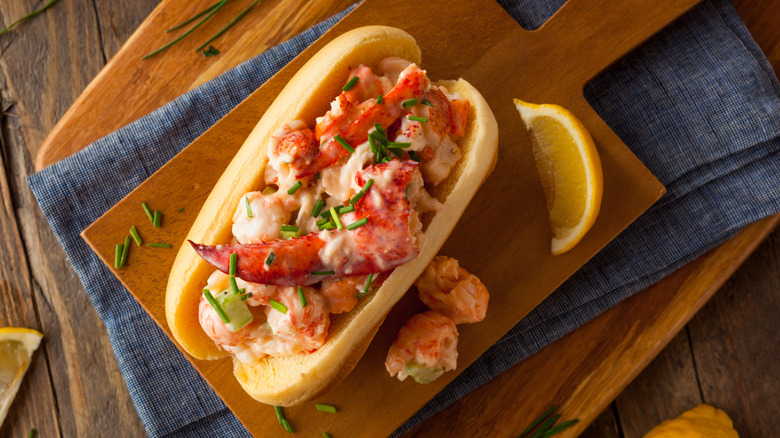 A lobster roll on a cutting board with chives