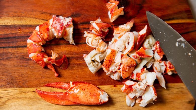 Chopped lobster tail, knuckle, and claw meat on a cutting board with a knife