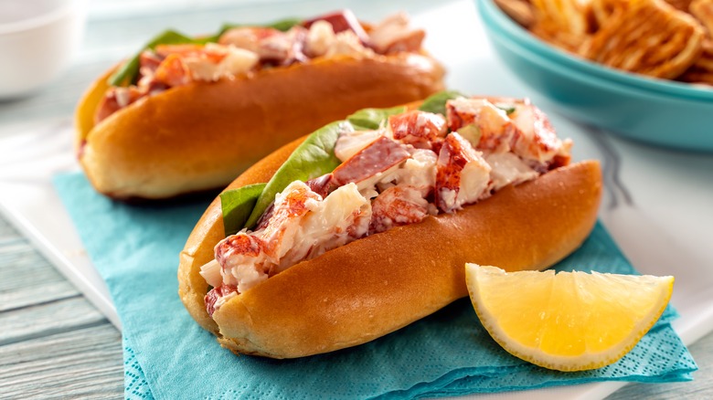 Two lobster rolls on a table with a wedge of lemon