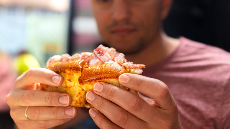A person holding a lobster roll with a toasted, buttered bun