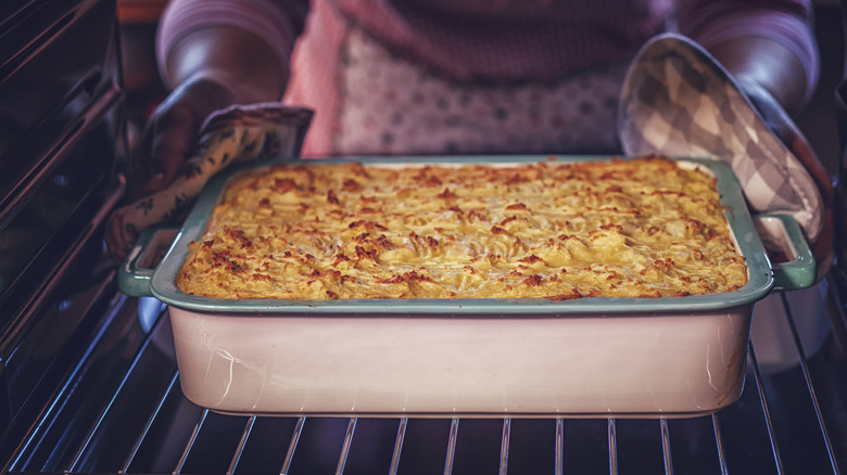 Woman placing shepherd's pie in oven