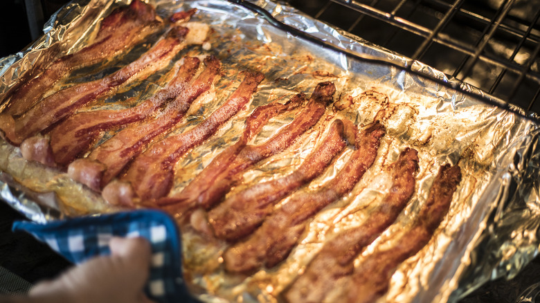 Person pulling bacon from oven