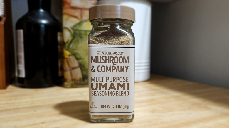 A brown-capped glass seasoning jar filled with brown powder, sitting on a kitchen counter