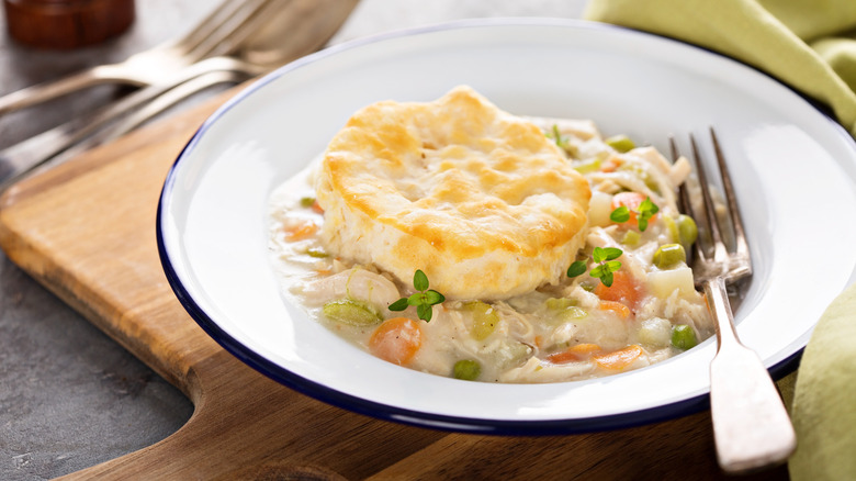 A bowl is filled with chicken pot pie and topped with biscuit dough.