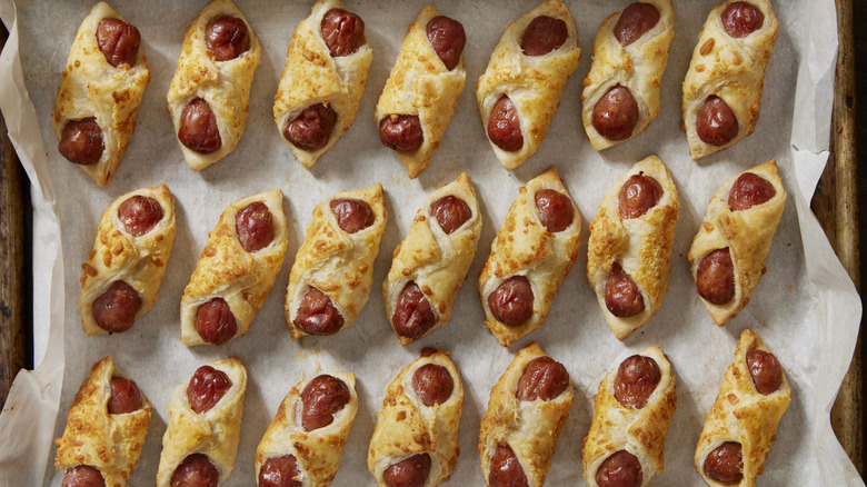 A tray is filled with rows of mini pigs in a blanket.