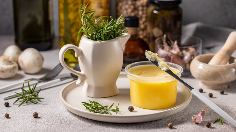 Bowl of ghee with container of rosemary