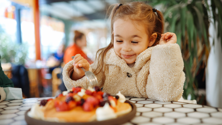 A small child eating a pancake at a restaurant