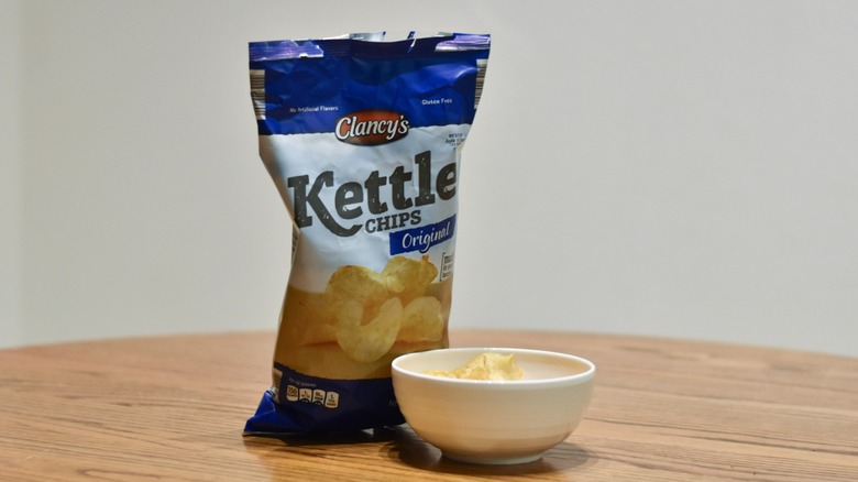 A bag of Clancy's kettle chips next to a white bowl of chips