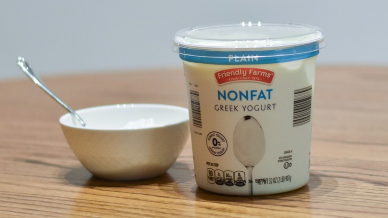 A container of Friendly Farms nonfat Greek yogurt next to a white bowl of yogurt