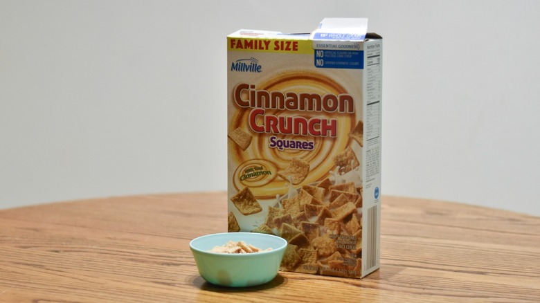 A box of cinnamon crunch squares cereal next to a bowl of cereal