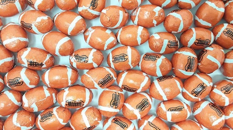 A bunch of football-shaped chocolates still in their foil wrappers decorated like footballs.