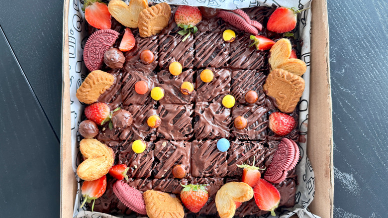 Candy-topped brownie batch in container on black table