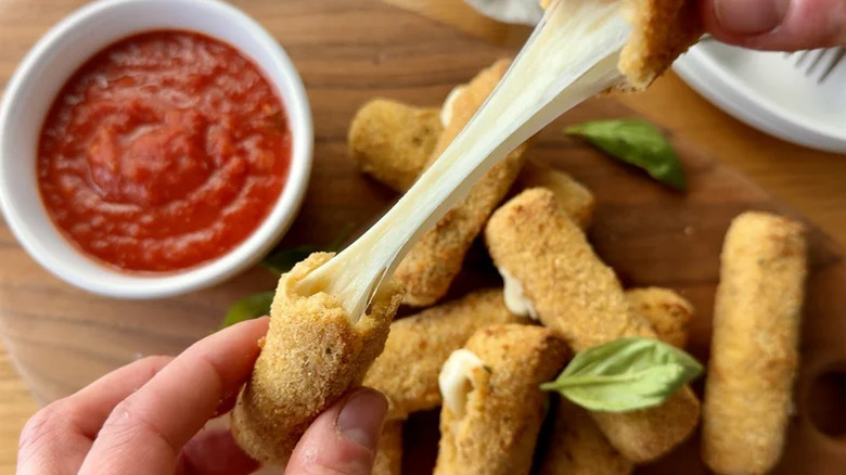 Mozzarella sticks being stretched to reveal the melted cheese