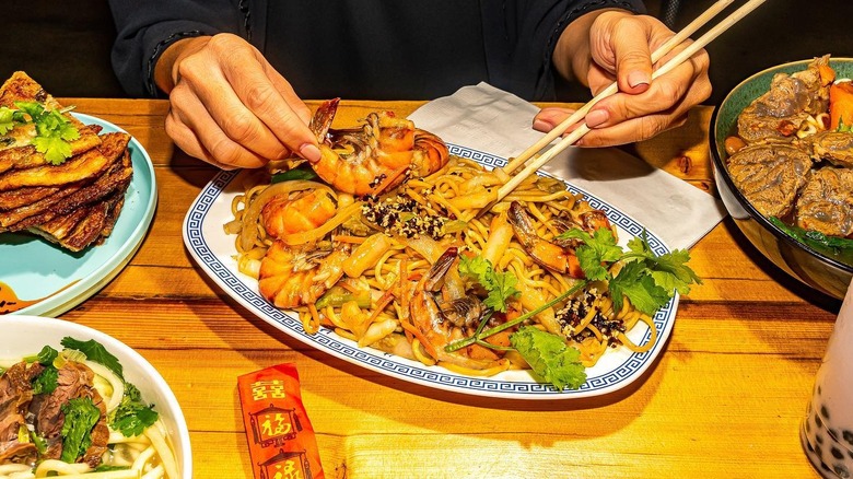 A person eating sir-fried noodles at DeKalb Market Hall