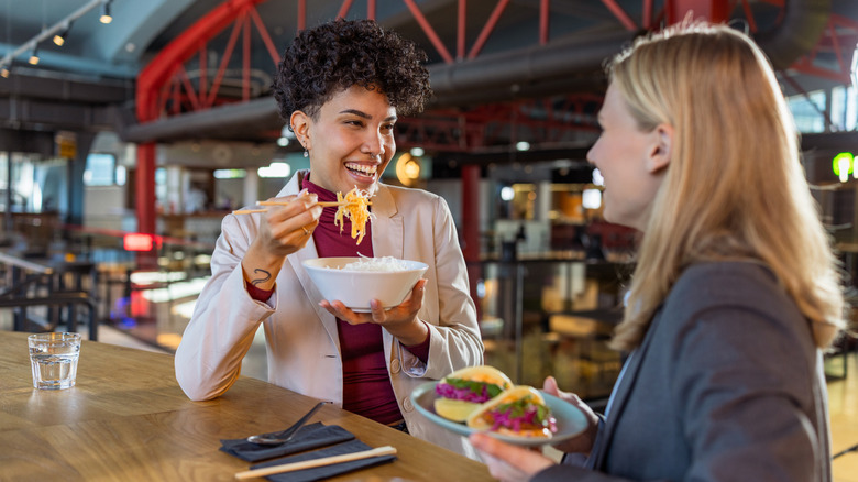 Two people eating food at a mall food court