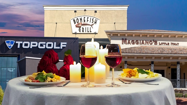 Chain restaurant storefronts behind romantic table with wine glasses