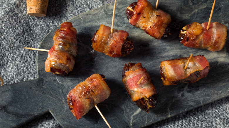 Bacon-wrapped dates on a granite cutting board