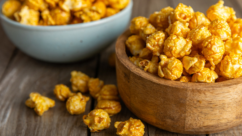 Two bowls of caramel popcorn on a wooden table