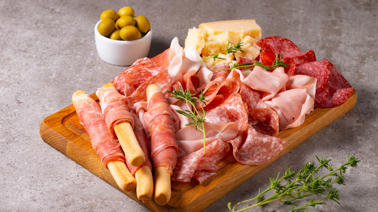 A charcuterie boar with cured meats, cheese, and green olives