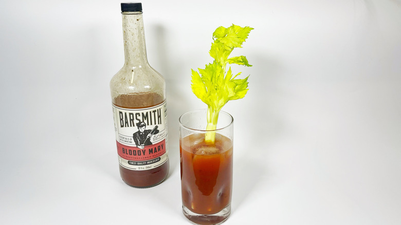 A bottle of Barsmith Bloody Mary mix next to a glass with celery garnish