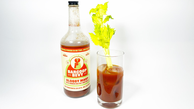A bottle of Barcoop Bevy next to a glass filled with mix and garnished with celery