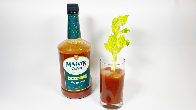 A jug of Major Peter's Bloody Mary mix next to a glass with celery garnish