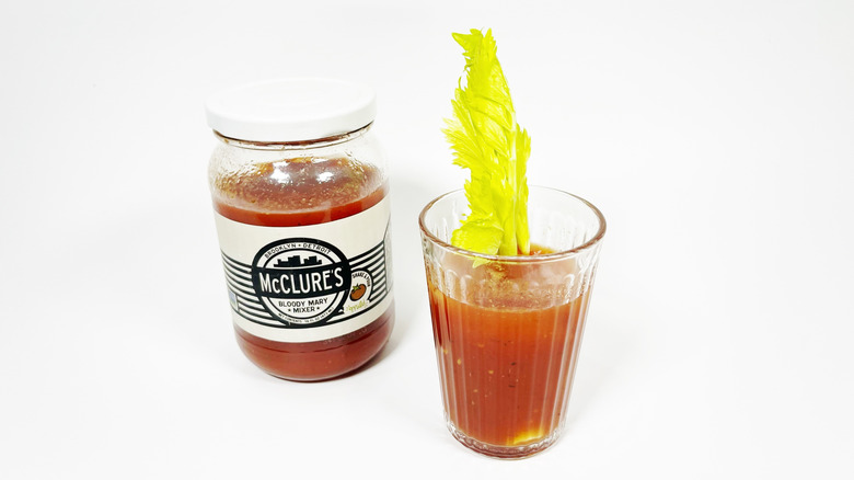 A jar of McClure's mild next to a glass filled with mix and garnished with celery