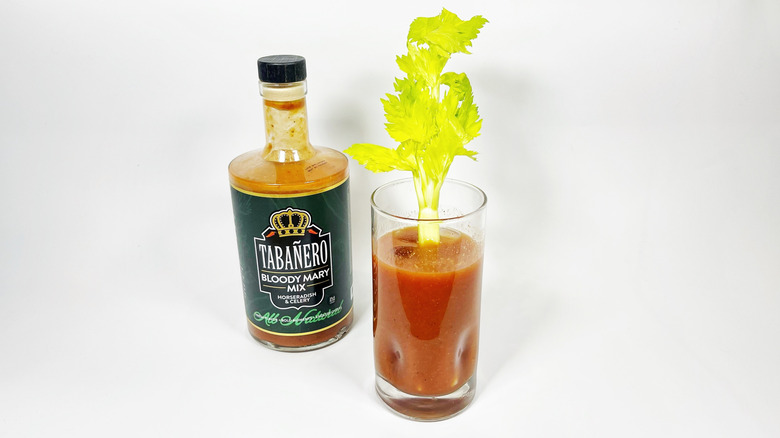 A bottle of Tabañero Bloody Mary next to a glass filled with mix and garnished with celery