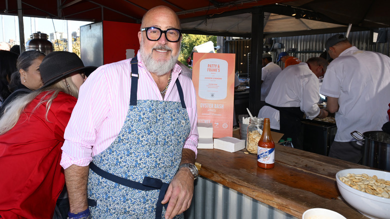Andrew Zimmern leaning on a bar at a cooking event