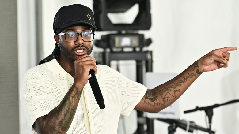 Chef Kwame Onwuachi speaking into a microphone at an event