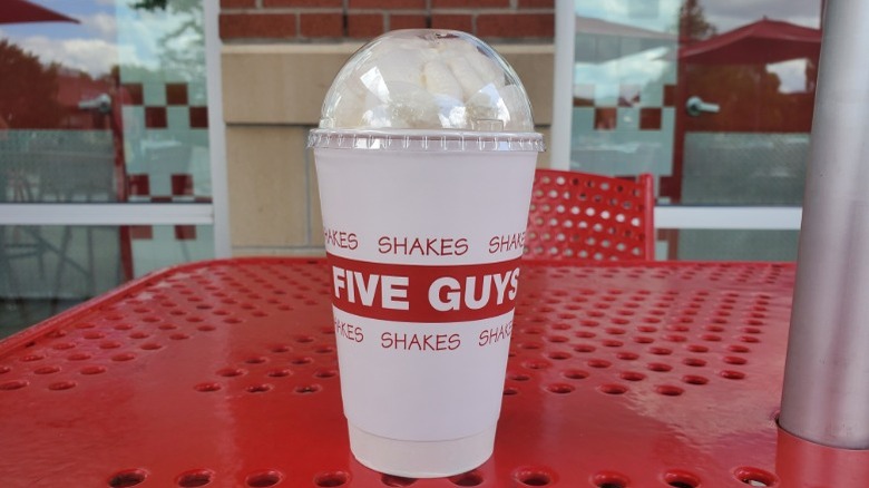 Five Guys chocolate milkshake placed on red table