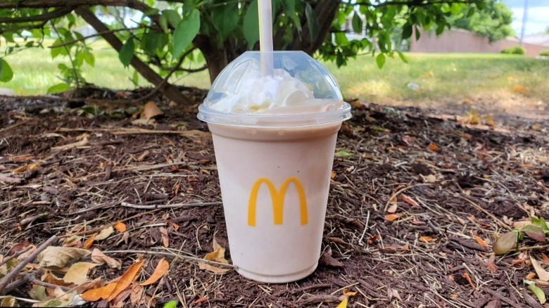 McDonald's chocolate shake sitting on pile of woodchips
