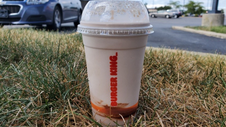 Burger King chocolate milkshake sitting in grass